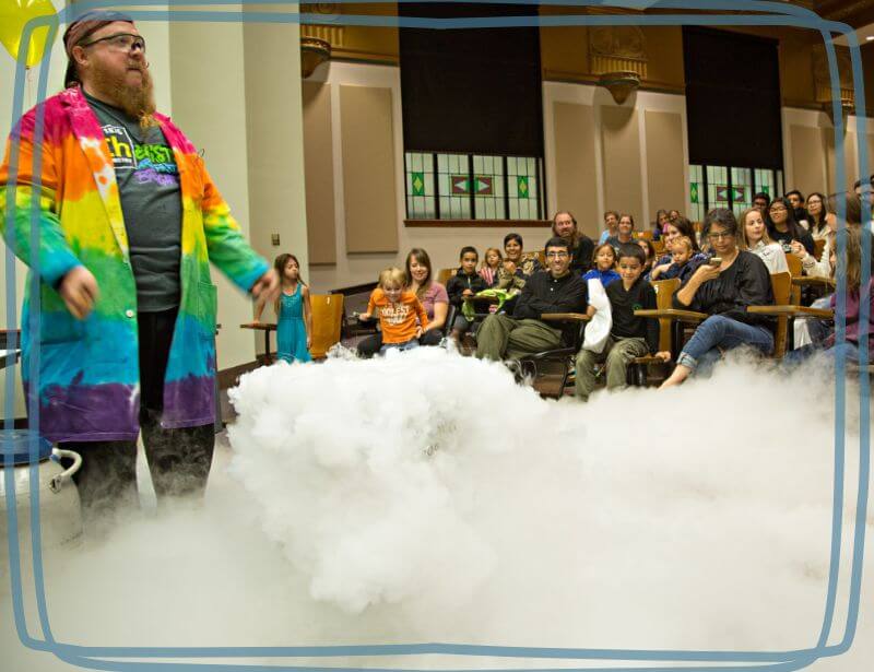 Chemistry professor with dry ice steam presentation in front of grop of school children