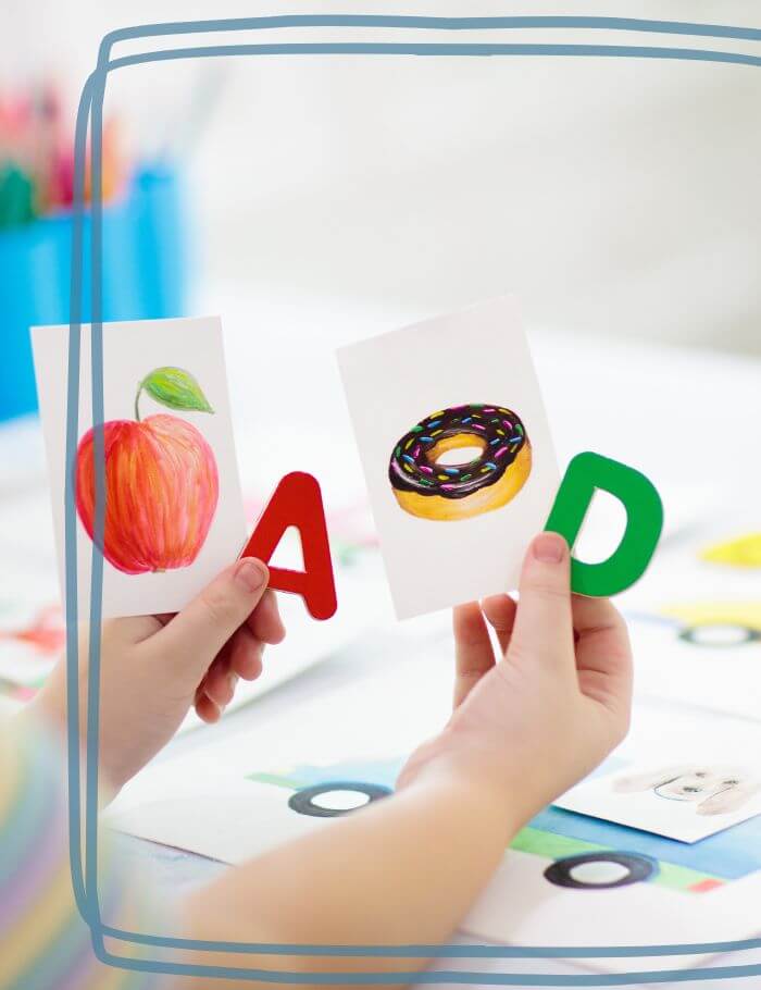 Elementary student holding alphabet cards and matching picture cards