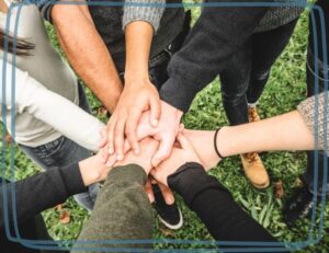 group of teenagers placing hands in the middle of a team circle